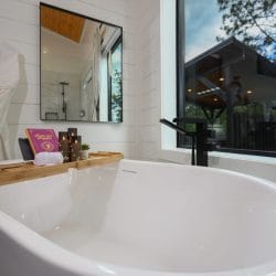 Bath tray across the freestanding tub with a book, candles and a rolled towel