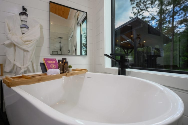 Bath tray across the freestanding tub with a book, candles and a rolled towel