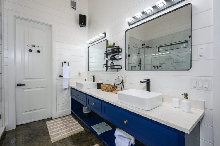 Navy double vanity with two vessel sinks and a long mirror