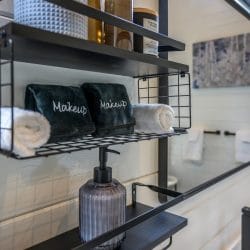 Shelf with rolled washcloths, a mirror and a soap dispenser