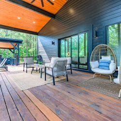 Covered deck with a sofa, two wicker egg chairs and sliding glass doors