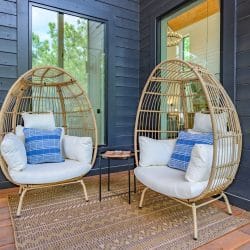 Two wicker egg chairs on the deck beside dark siding