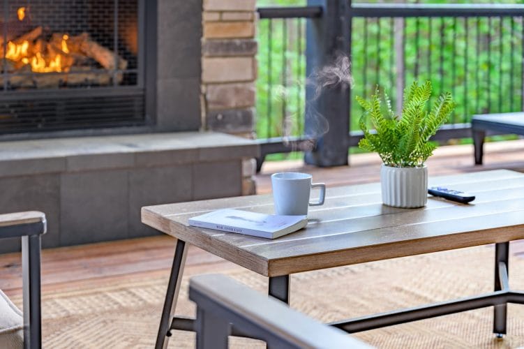 Coffee table with a mug and a book in front of the deck fireplace