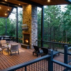 Covered deck with stone-clad pillars, a fireplace and a TV