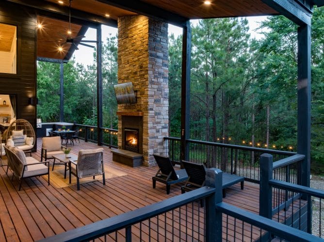 Covered deck with stone-clad pillars, a fireplace and a TV