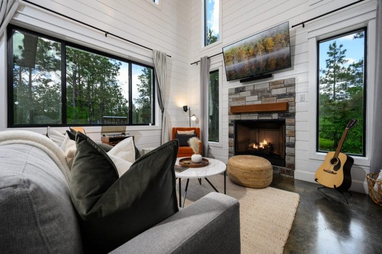 Sofa facing the fireplace and TV, an acoustic guitar standing by the window