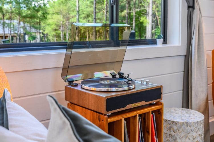 Record player on a wood console with a shelf of records
