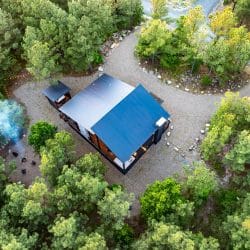 Aerial looking down on the cabin roof, a fire pit and the gravel drive loop