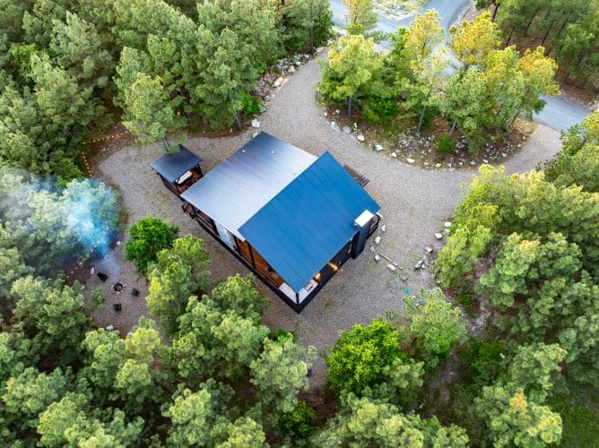 Aerial looking down on the cabin roof, a fire pit and the gravel drive loop